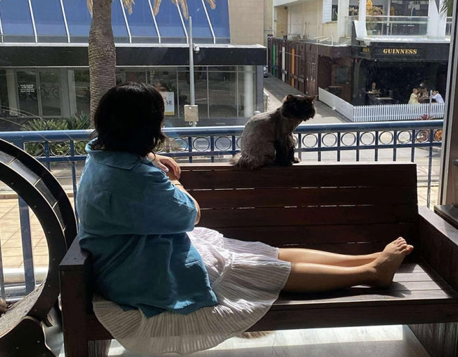 Woman sitting on balcony with cat Crazy Cat Cafe