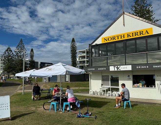 People seated on grass at NK Cafe Kirra