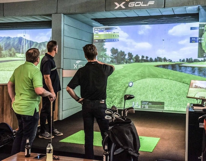 Three men playing golf indoors X-Golf 