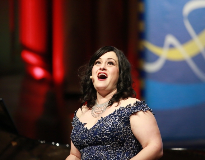 Singer Gabrielle Jack singing in front of red curtain Songs & Soiree