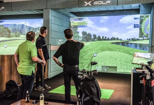 Three men playing golf indoors X-Golf 