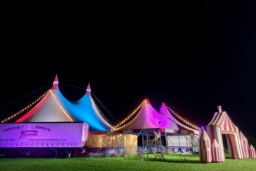 Circus performers and colourful big top tent at night