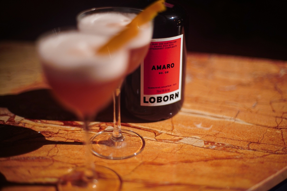 Bottle of amaro and two glasses on a wooden table at Loborn Tamborine Mountain 
