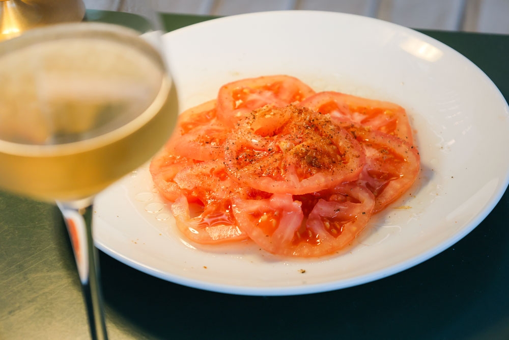 Glass of wine and a plate of pickled tomatoes