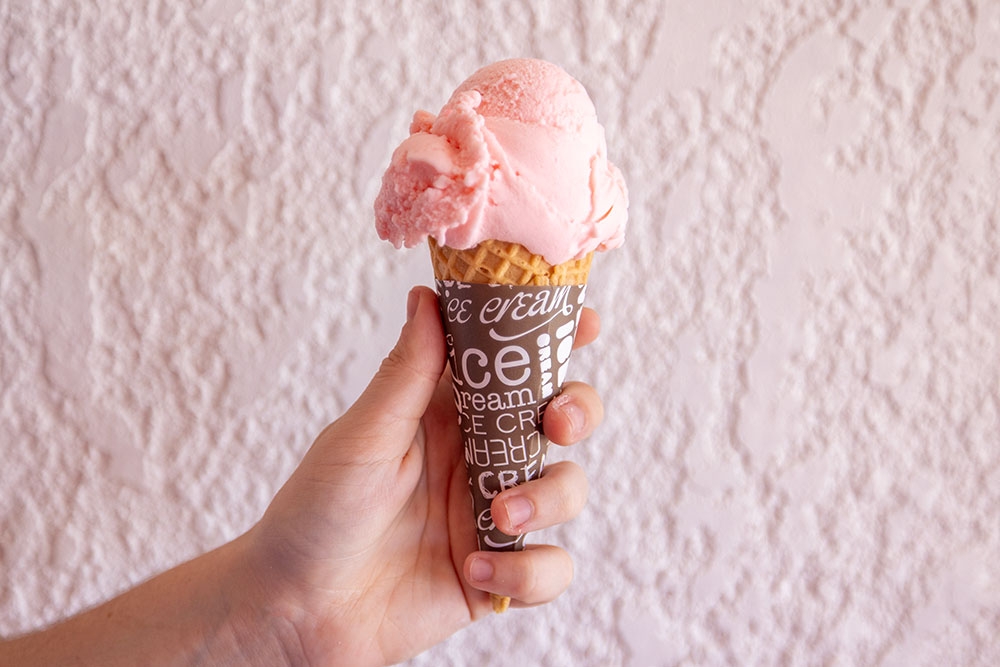Hand holding strawberry ice cream cone 