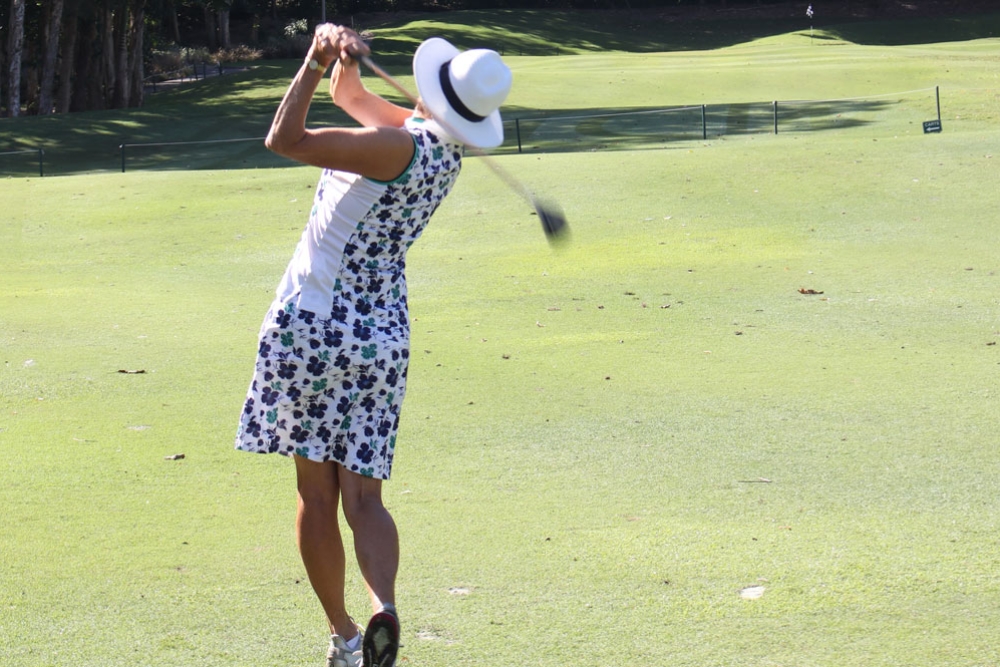 A lady swinging a golf club, Lexus of Southport Golf Day