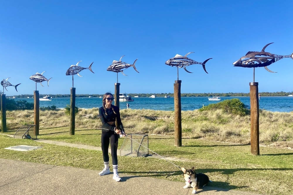 Girl with dog in front of the Marine Paradie Foreshore fish sculptures 