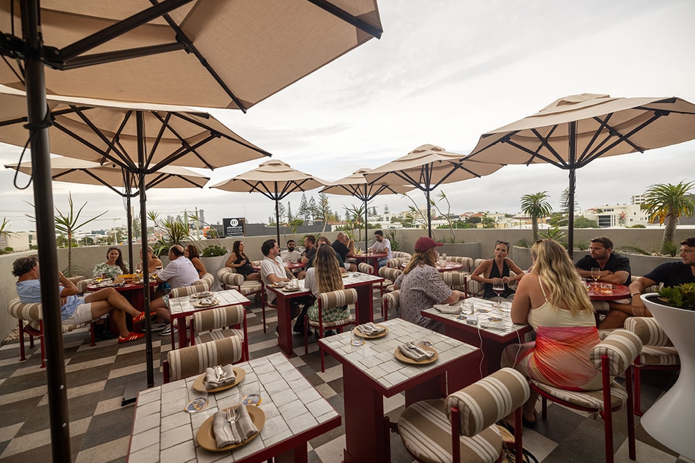Crowd of people under umbrellas on terrace at Sueño Rooftop at 