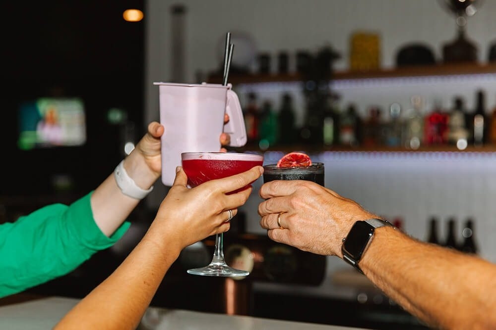 3 people cheering with a drink at X-Golf 